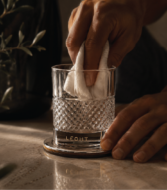 Hands wiping the Lēoht diamond-cut vessel with a soft cloth